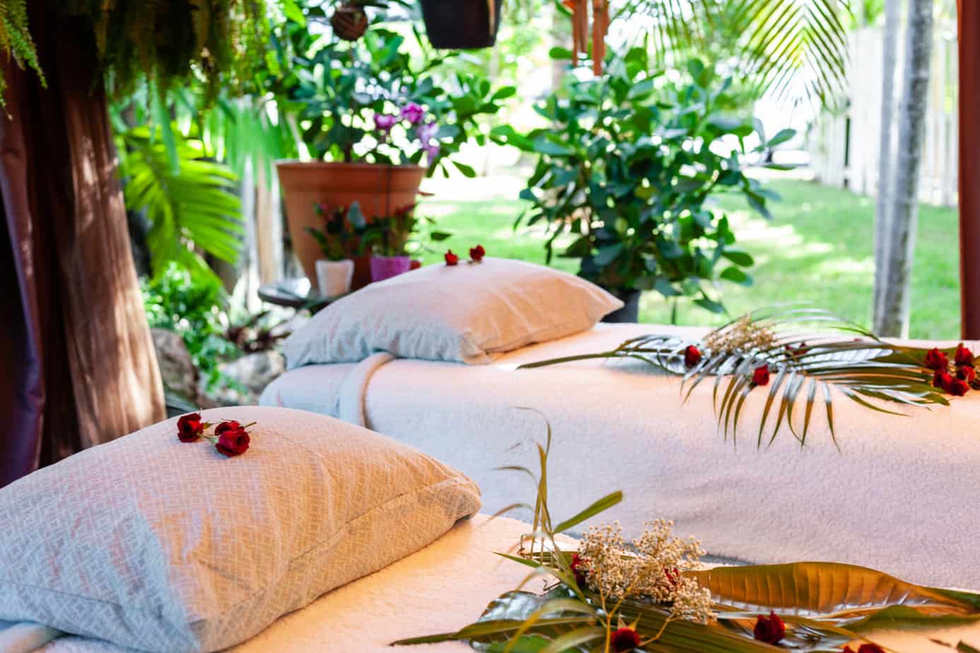 Two massage beds in an outdoor room adorned with plants and flowers, offering the perfect setting for an invigorating outdoor massage in Fort Lauderdale.