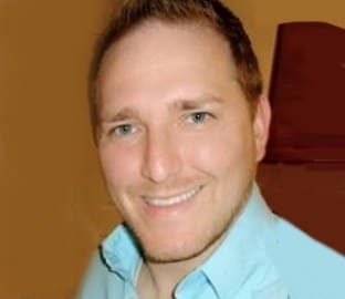 Matthew Baker, a man in a blue shirt, smiles for the camera.