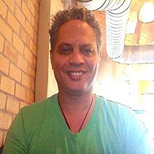 A man in a green shirt smiling at a table.