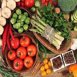 A variety of vegetables are arranged on a wooden table.