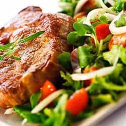 A plate of meat and salad on a white plate.