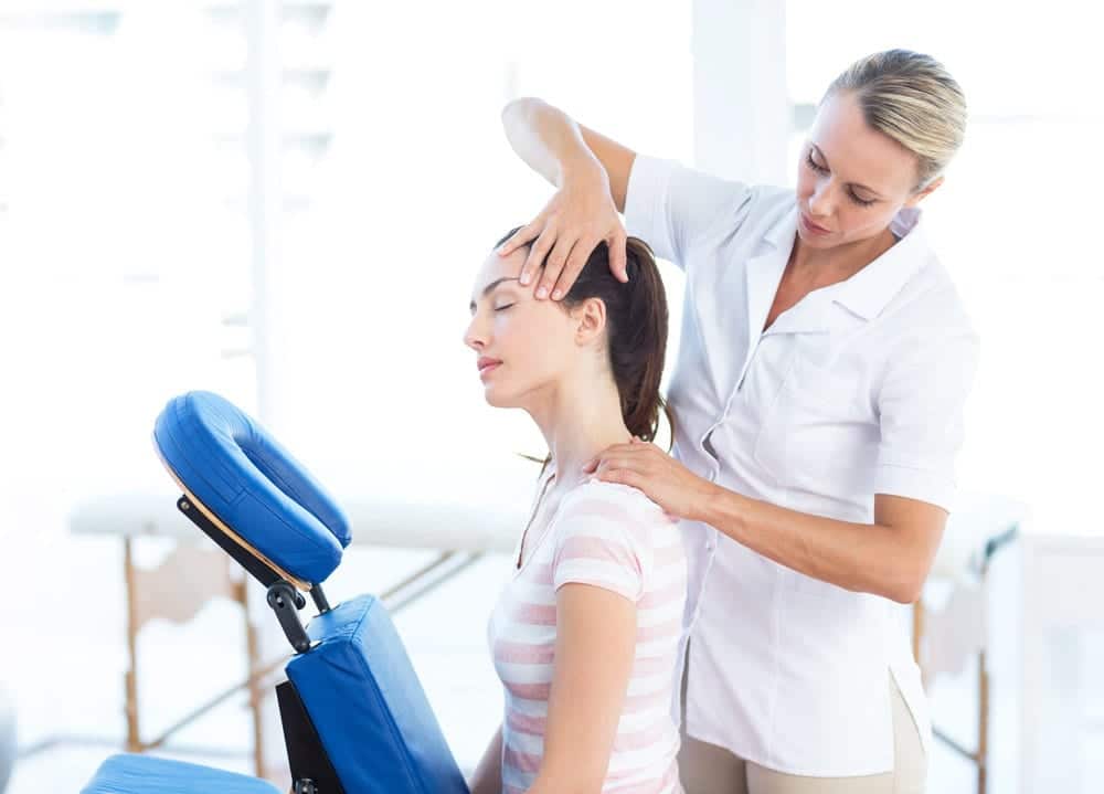 A woman is getting her neck massaged by a physiotherapist.