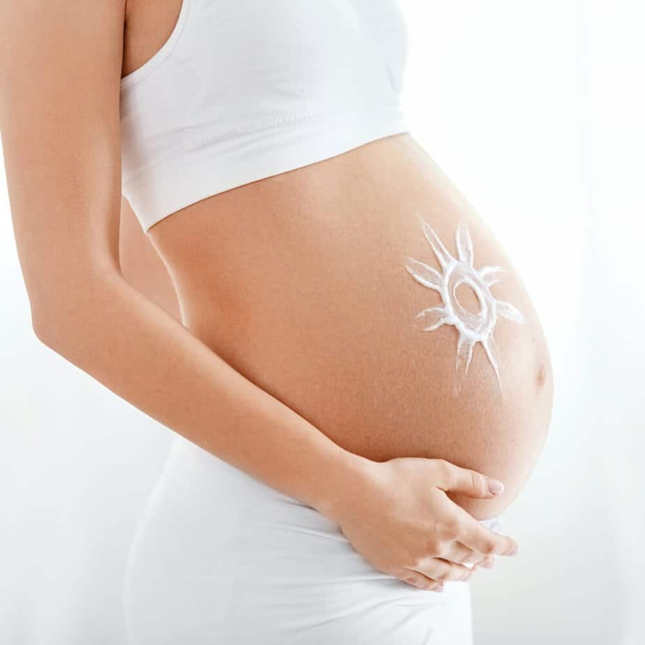 A pregnant woman with a sun painted on her stomach.