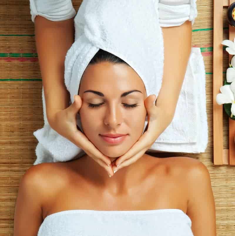 A woman getting a facial massage at a spa.