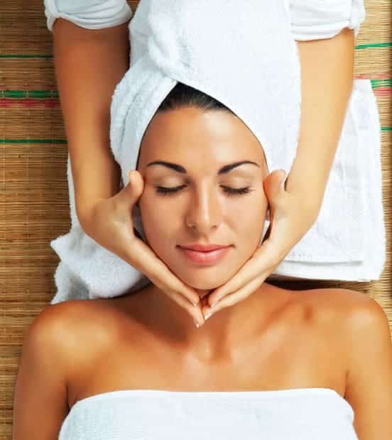 A woman getting a facial massage at a spa.