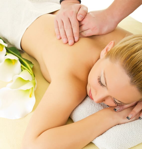 A woman lying down on a towel with hands on her back.
