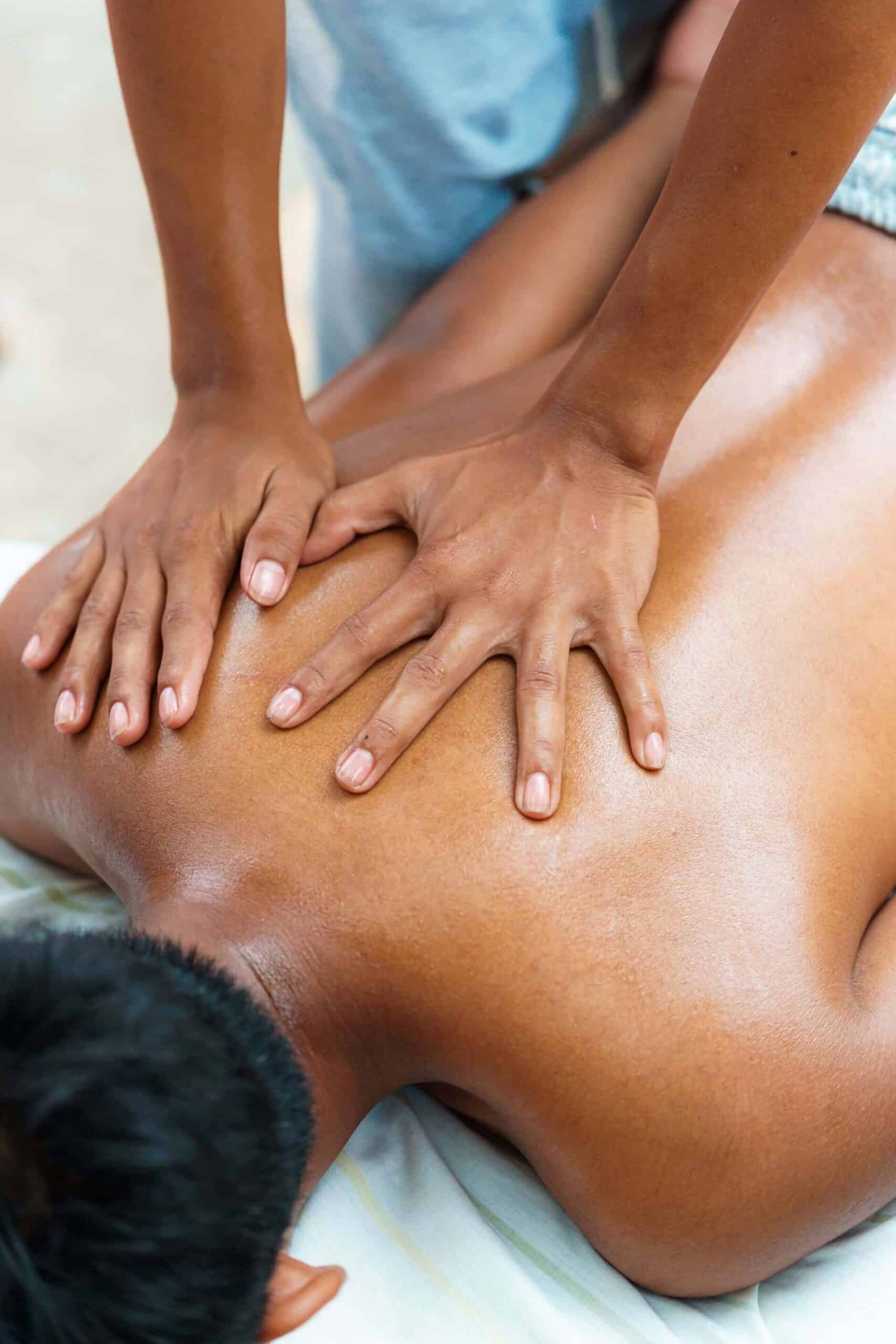 A Person Receives A Back Massage As Another Person Applies Pressure With Both Hands On Their Upper Back.